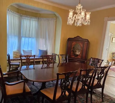 a dining room with a table and chairs and a chandelier at The White House in Plainfield