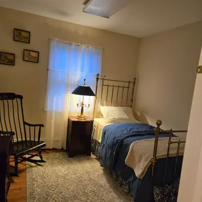 a bedroom with a bed and a lamp and a window at The White House in Plainfield