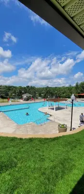 a large swimming pool with people in the water at Vdara Pocono Home in Tobyhanna