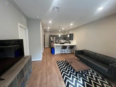 a living room with a black couch and a kitchen at 315 Brand New 1 Bedroom 1 Bath 1 Full Kit 1 Liv in Dunellen