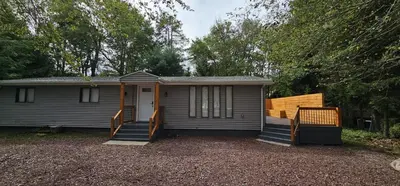 a small grey house with a porch and stairs at Aria Pocono Home in Tobyhanna