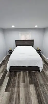 a bedroom with a large white bed and wooden floors at Aria Pocono Home in Tobyhanna