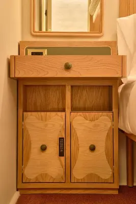 a wooden nightstand with a mirror and a bed at Now Now NoHo in New York