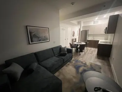 a living room with a black couch and a kitchen at Luxury 2 BD unit in Financial District in New York
