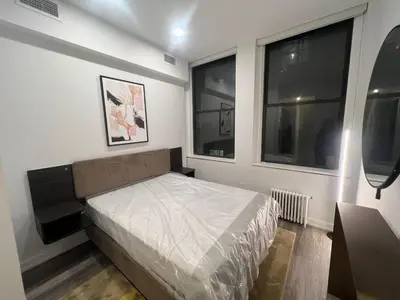 a small bedroom with a bed and two windows at Luxury 2 BD unit in Financial District in New York