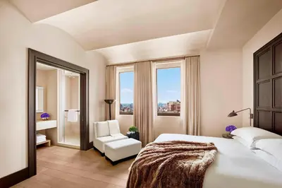 a bedroom with a bed and a chair and a window at The New York EDITION in New York