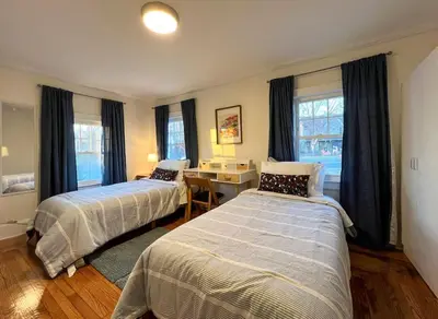a bedroom with two beds and a desk and windows at Quaint Renovated Single Family in Matawan