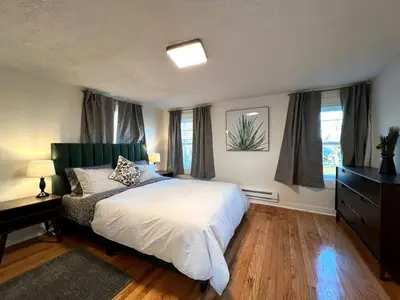 a bedroom with a bed and a dresser and windows at Quaint Renovated Single Family in Matawan