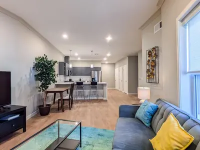 a living room with a blue couch and a kitchen at 213 Brand New 3 Bedroom 2 Bath 1 Full Kit 1 Liv in Dunellen