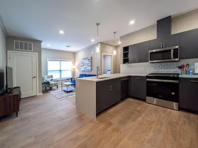 a large kitchen with black cabinets and a living room at 222 Brand New 2 Bedroom 1 KIT 2 BATH 1 Living in Dunellen