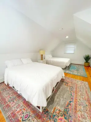 a white bedroom with two beds and a rug at Luxe 10 guest Cottage Ski-Golf-Firepit-Lakes-Hike in Vernon Township