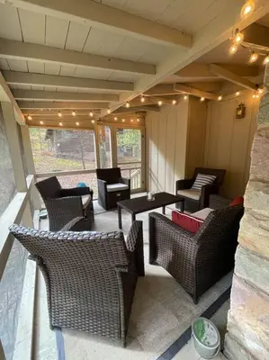 a patio with wicker chairs and tables and lights at Racc00ns Retreat in Lake Harmony
