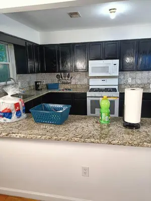 a kitchen with black cabinets and a counter top at Fada Guest House - 38 Yates Ave Newark in Newark