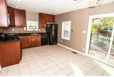 a kitchen with brown cabinets and a black refrigerator at 107 Quaint Renovated Single Family 3 Bdrm House in Old Bridge