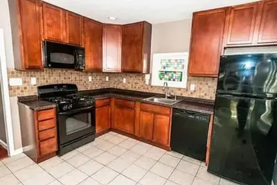 a kitchen with wooden cabinets and a black refrigerator at 107 Quaint Renovated Single Family 3 Bdrm House in Old Bridge