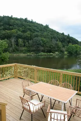 a wooden deck with a table and chairs and a lake at Upper Delaware River House in Equinunk