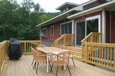 a wooden deck with a table and chairs on it at Upper Delaware River House in Equinunk