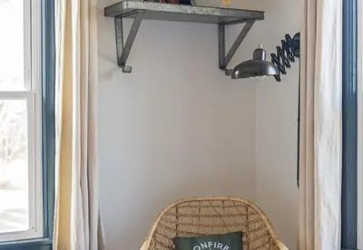 a shelf on a wall with a wicker chair at The Arnold House in Livingston Manor