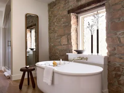 a large white tub in a bathroom with a stone wall at Stockton Inn in Stockton