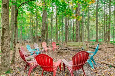 a group of chairs and a table in the woods at Home with Hot Tub and Arrowhead Lake Community Perks! in Pocono Lake