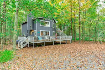 a house in the middle of a forest at Home with Hot Tub and Arrowhead Lake Community Perks! in Pocono Lake