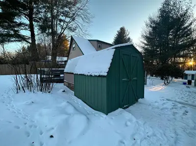 a green shed covered in snow in a yard at Lakefront with Lots of Light and Private Dock Access in Ferndale