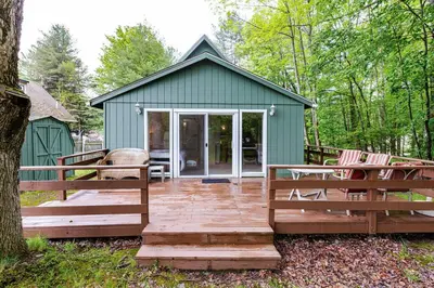 a green shed with a wooden deck and chairs at Lakefront with Lots of Light and Private Dock Access in Ferndale