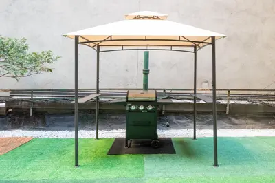 a bed with an umbrella on a green floor at Modern 3Bd Rose Hills Manhattan Terrace Space in New York