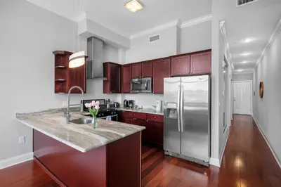 a kitchen with a stainless steel refrigerator and wooden cabinets at Stylish 1BR - Rooftop Pool in Philadelphia