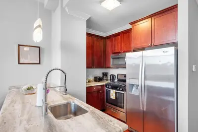 a kitchen with wooden cabinets and a stainless steel refrigerator at Stylish 1BR - Rooftop Pool in Philadelphia
