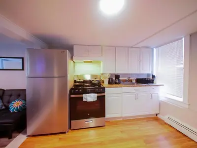 a kitchen with a stainless steel refrigerator and white cabinets at Bright and Airy Studio Apt Minutes to NYC in Jersey City