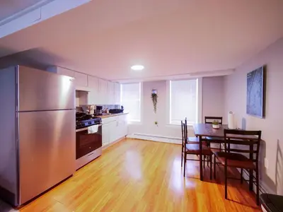 a kitchen with a table and a stainless steel refrigerator at Bright and Airy Studio Apt Minutes to NYC in Jersey City