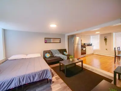 a bedroom with a bed and a living room at Bright and Airy Studio Apt Minutes to NYC in Jersey City