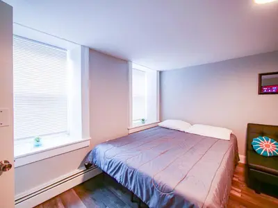 a bedroom with a bed and two windows at Bright and Airy Studio Apt Minutes to NYC in Jersey City