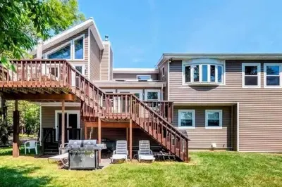 a house with a deck and chairs in the yard at 5-Bedroom Lakefront, private beach wifi AC boat & in Tobyhanna