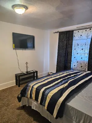 a bedroom with a bed and a flat screen tv at UD guest house in East Orange