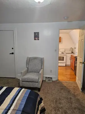 a bedroom with a bed and a chair and a kitchen at UD guest house in East Orange