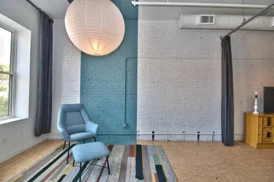 a living room with a blue chair and a lamp at Wonder Honesdale -Loft A2 in Honesdale
