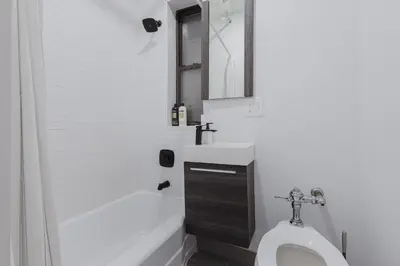 a bathroom with a toilet and a sink and a mirror at 2 Bedroom Modern Unit in Central Manhattan in New York