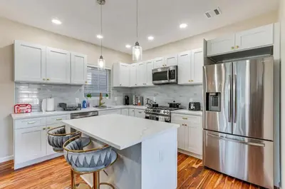 a kitchen with white cabinets and a stainless steel refrigerator at Townhouse - Urban Living with Rooftop Deck! in Newark