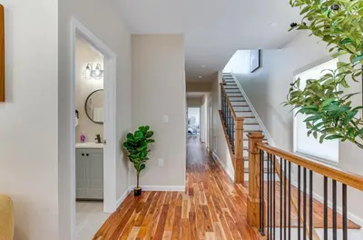 a hallway with white walls and a staircase with potted plants at Townhouse - Urban Living with Rooftop Deck! in Newark