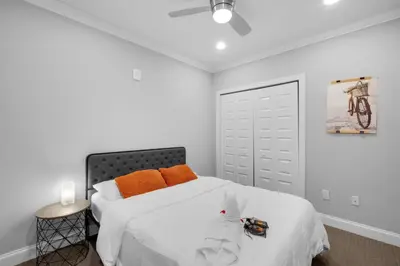 a bedroom with a bed with white sheets and orange pillows at Chic NoLibs 1BR - Pool & Gym in Philadelphia
