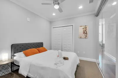 a white bedroom with a bed with orange pillows at Chic NoLibs 1BR - Pool & Gym in Philadelphia