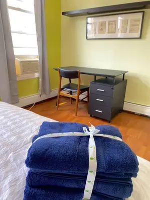 a bedroom with a bed with blue towels and a desk at 3-bedrooms Journal Square near NYC in Jersey City