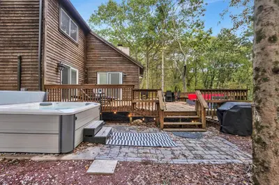 a hot tub in a yard next to a house at Nature's Paradise with Hot Tub and Fire Pit in Lake Harmony