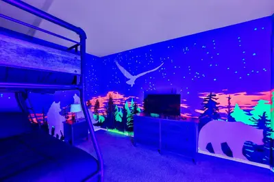 a bedroom with a bed with a dinosaur themed wall at Nature's Paradise with Hot Tub and Fire Pit in Lake Harmony
