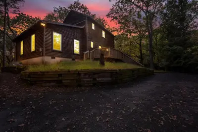 a house on a hill with the sunset in the background at Nature's Paradise with Hot Tub and Fire Pit in Lake Harmony