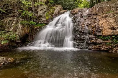 a waterfall on the side of a rocky cliff at Nature's Paradise with Hot Tub and Fire Pit in Lake Harmony