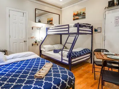 a bedroom with two bunk beds and a table at Metropolitan Studio Apartments Manhattan in New York