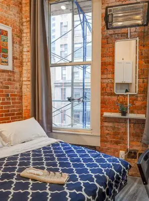 a bedroom with a bed and a large window at Metropolitan Studio Apartments Manhattan in New York